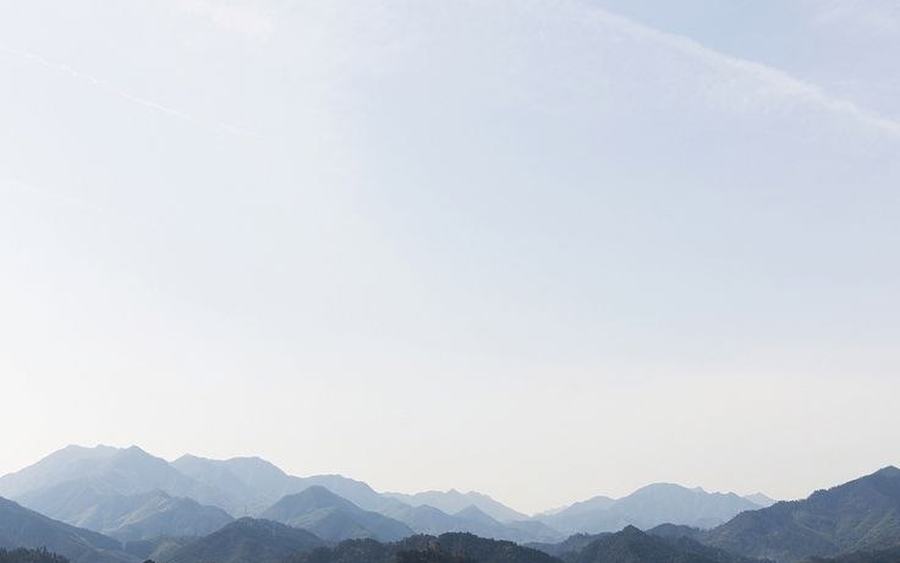 Expansive layered mountain wilderness shrouded in soft morning mist